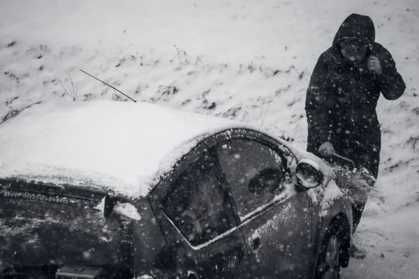 person scrapping snow of the car